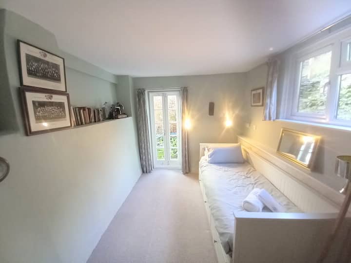 Dormitorio de jardín con ventanas francesas hacia los escalones hasta la terraza: ¡este era mi dormitorio cuando era adolescente y todavía tiene algunos de esos libros!
