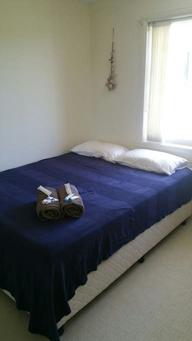 Queen bed with linen, towels, toiletries