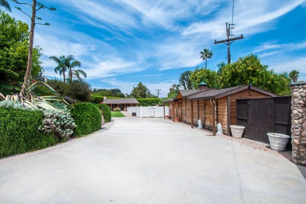 Large, gated driveway next to barns and horse arena.