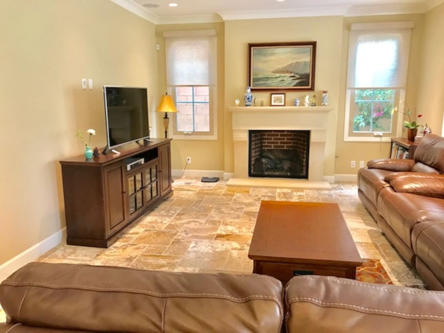 Spacious living room with big screen TV, comfy leather couch and fireplace.