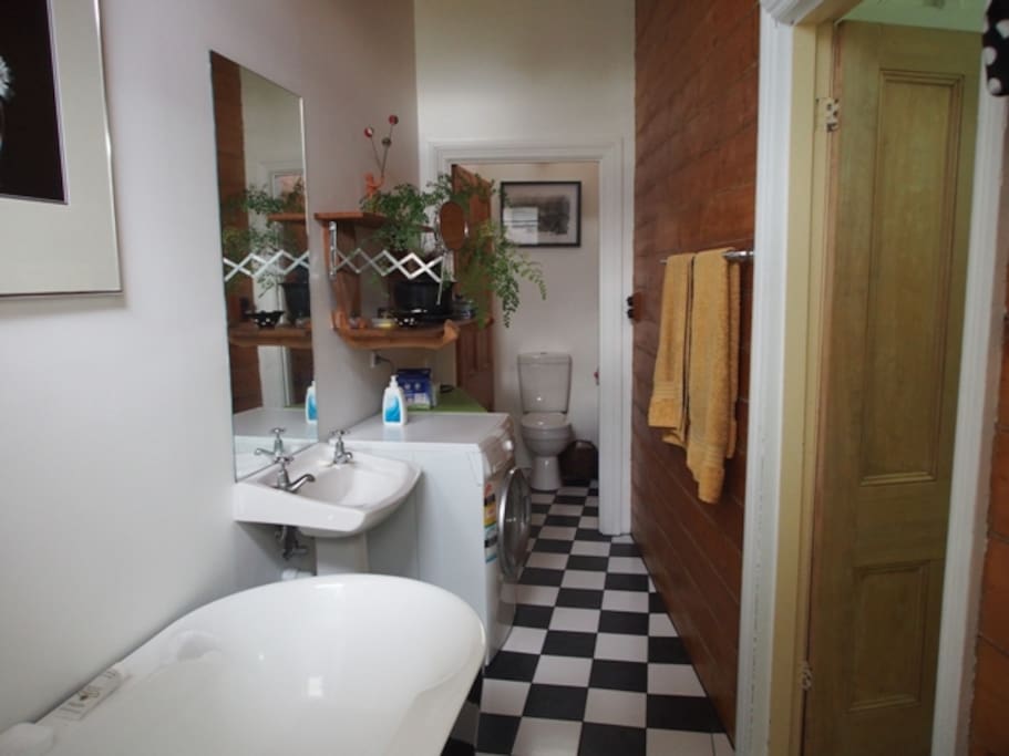 small but beautiful bathroom has a bath, shower, toilet and washing machine