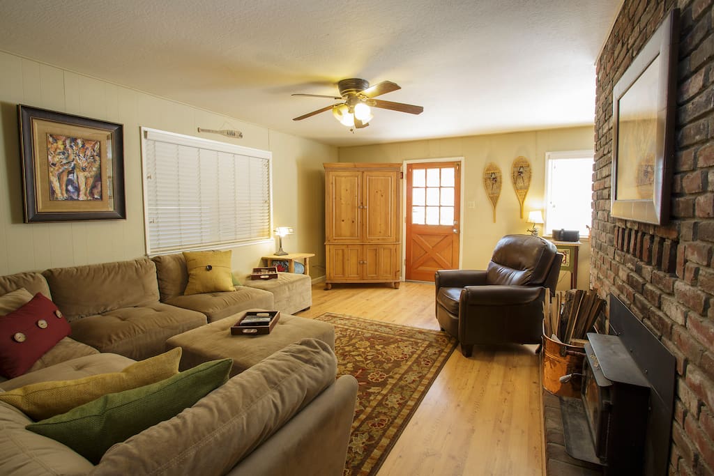 Living Room with large flat screen TV w/ Ruko and Cable, ceiling fan, wood burning stove. That is the front door you see there.