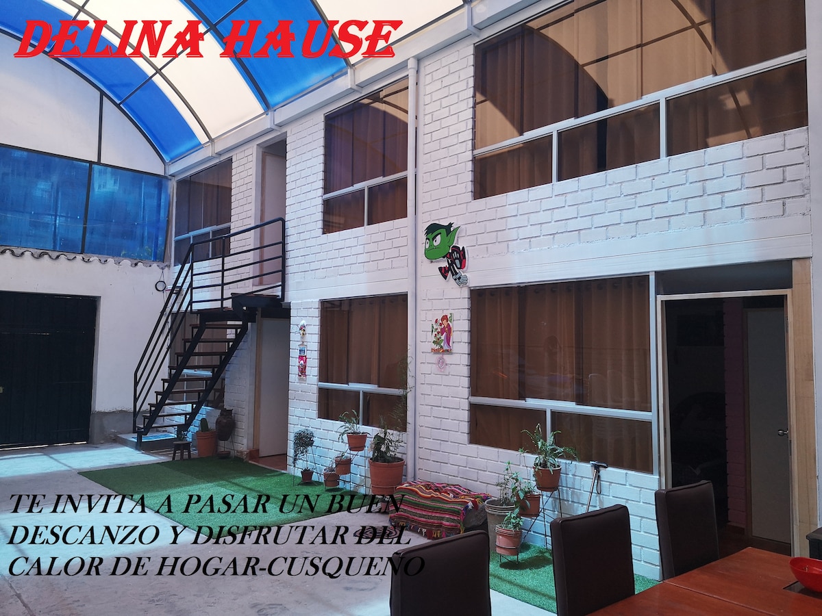 A central courtyard is visible, showcasing a two-story building with large windows allowing ample natural light. Colorful decorations adorn the walls, while a staircase leads to the upper level. Seating areas are present, promoting a comfortable space for relaxation and socializing.