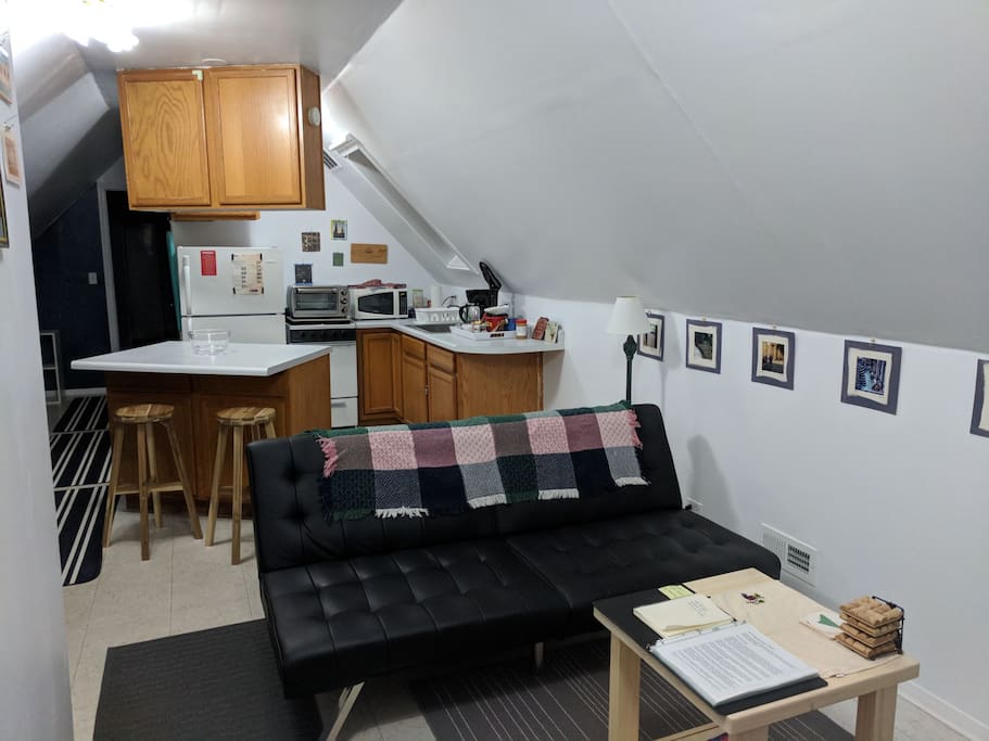 Front sitting area and kitchen. House manual and guidebook on the coffee table. Futon folds down into a bed for a 3rd guest.
