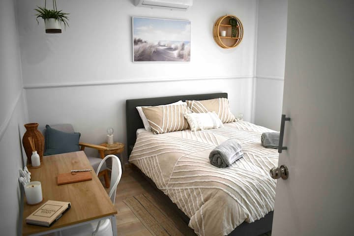 Glavna spavaća soba s bračnim krevetom i radnim stolom.