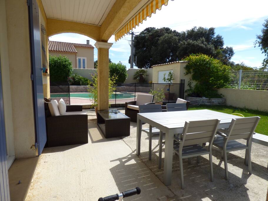 Coin repas et détente avec salon de jardin, accès depuis la cuisine et le séjour. Accès sécurisé vers la piscine avec barrière souple aux normes françaises