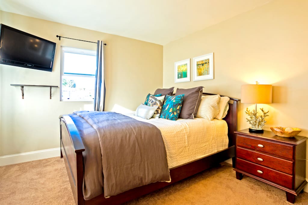 Comfortable King Bed has pillow top mattress, luxury bedding and a wall mounted flat screen TV.