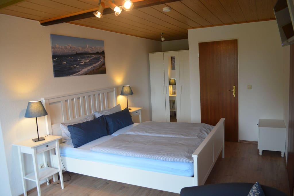 Kombiniertes Wohn-/Schlafzimmer mit Doppelbett, Schrank und Sesseln.