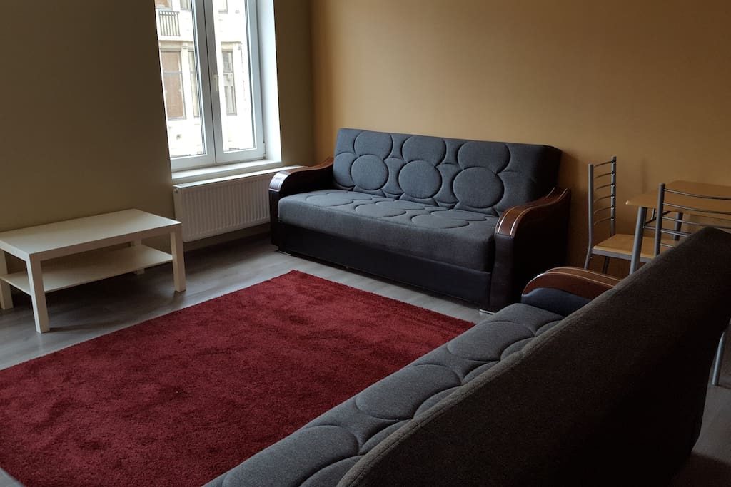 Appartement de gauche situé au 3ème étage : salle de séjour avec 2 canapés-lits, une cuisine équipée et une télévision.