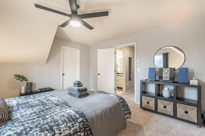 Dormitorio con cama queen, tomacorrientes USB y un pequeño estéreo.