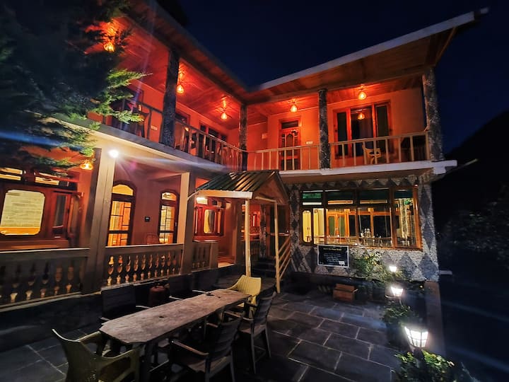 The outdoor dining table at night — stone patio, warm light, and the forest pressing in