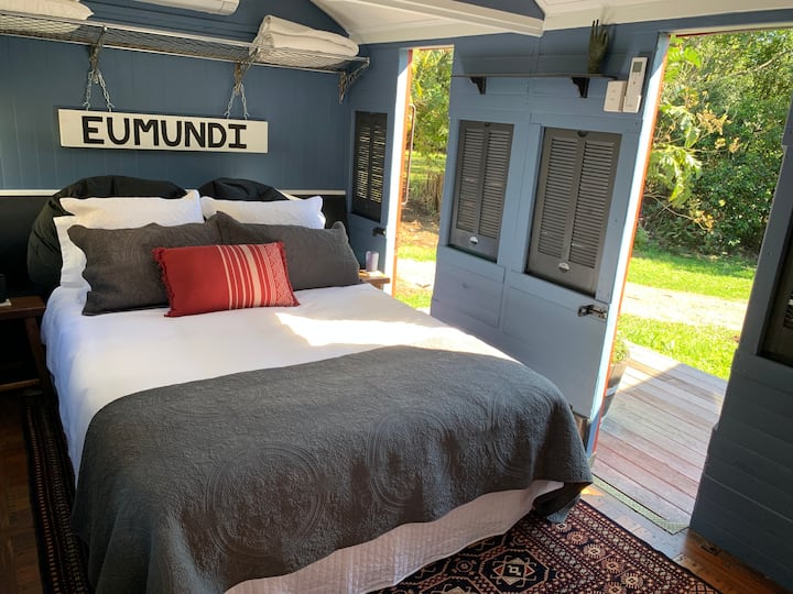 The queen-sized bed has luxury bed linens, and two doors opening out onto the deck and view bring in light, fresh air, and a relaxed country vibe.