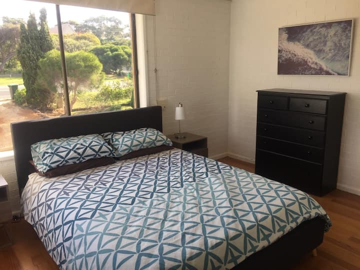 Dormitorio en la planta superior con moderna suite de dormitorio tamaño queen, suelos de madera, armarios empotrados altos e incorporados con puertas con espejos y vistas al jardín delantero.