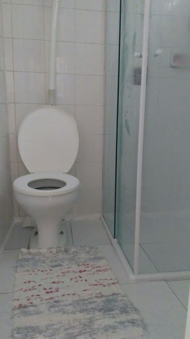 Um banheiro com box de vidro, pia e suporte para toalhas.
