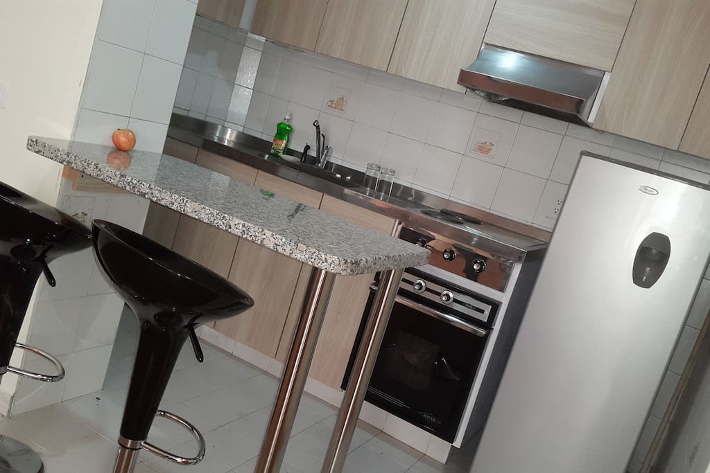 Cocina, Nevera y utensilios para cocinar con elegantes asientos.