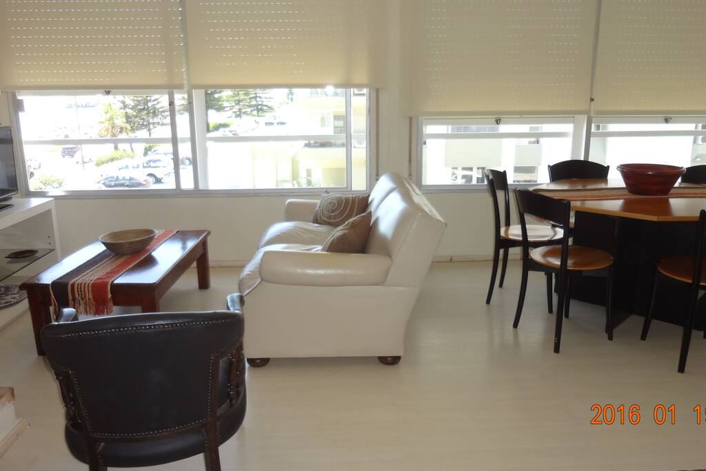 Cómodo living comedor en planta principal con amplios ventanales y vista al mar.