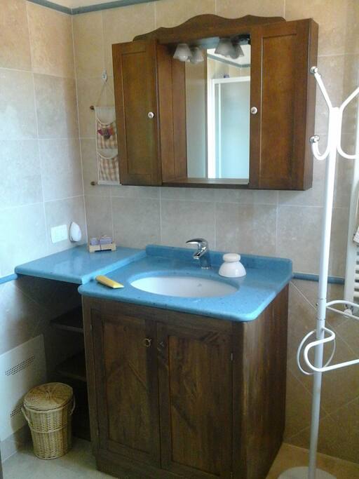 Particolare del bagno, attrezzato di asciuga capelli, doccia e biancheria bagno.