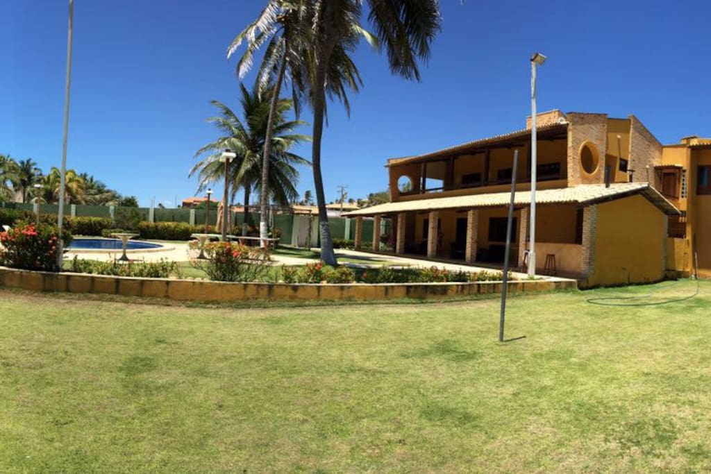 Vista campo de futebol, casa e piscina.