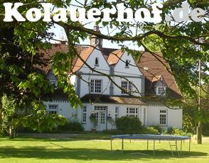 A large, charming farmhouse is set within a spacious garden, framed by leafy trees. The building features multiple windows and a sloped roof. A trampoline can be seen in the foreground, emphasizing a child-friendly environment.