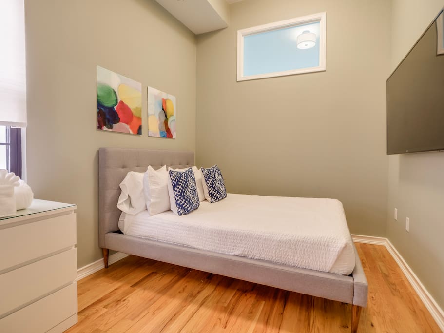 The queen-size bed in the second bedroom has an elegant tufted headboard and promises a luxurious sleeping experience.