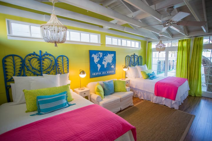 Bedroom with two queen size beds, a love seat and a flat screen TV.  A large deck off of the bedroom.