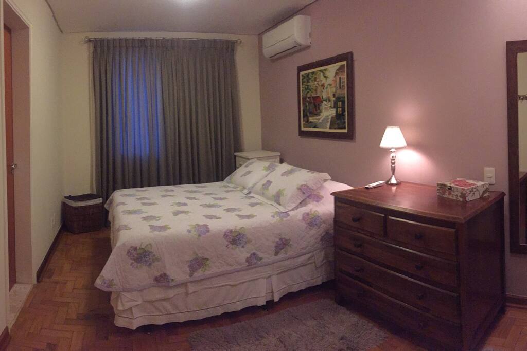 Suíte espaçosa com cama queen, ar condicionado e armário planejado.