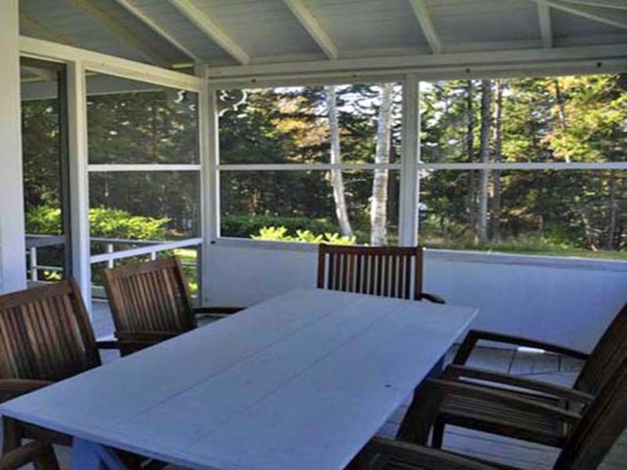 A nice screened in porch with a large dinner table.