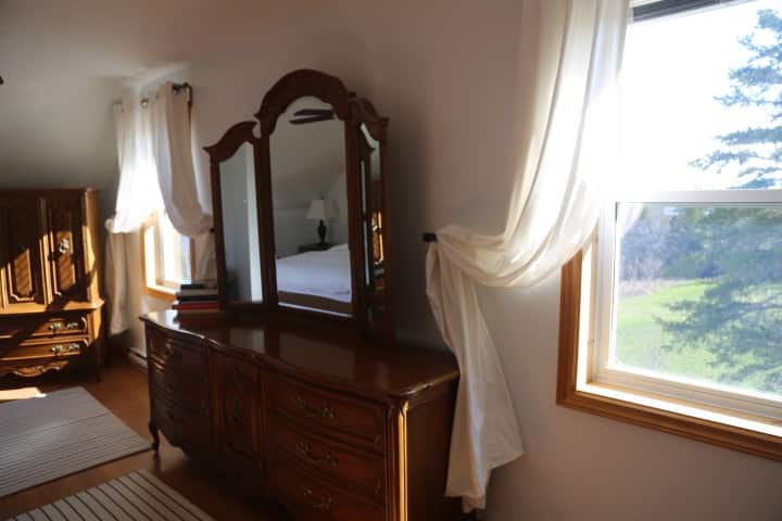 The master bedroom features carved wood furniture and a 180 degree view of the sea to the left and forest to the right.