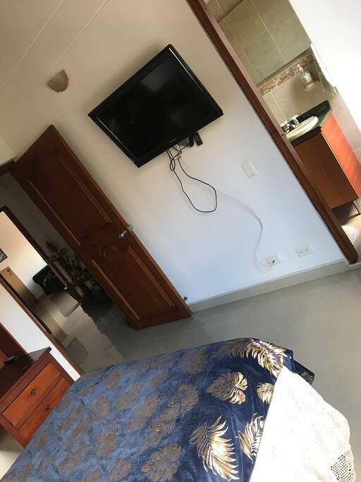 Hacia la izquierda se ve la entrada a la habitación, pegado ala pared un TV moderno.