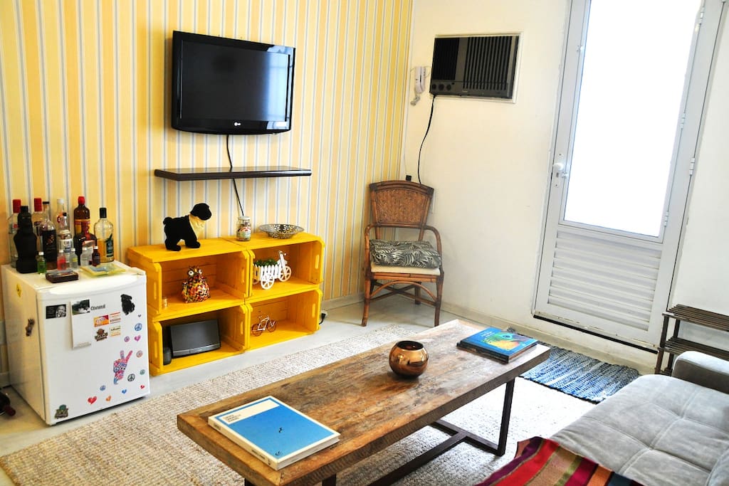 Frigobar disponível para uso, TV, decorações e móveis úteis na sala.