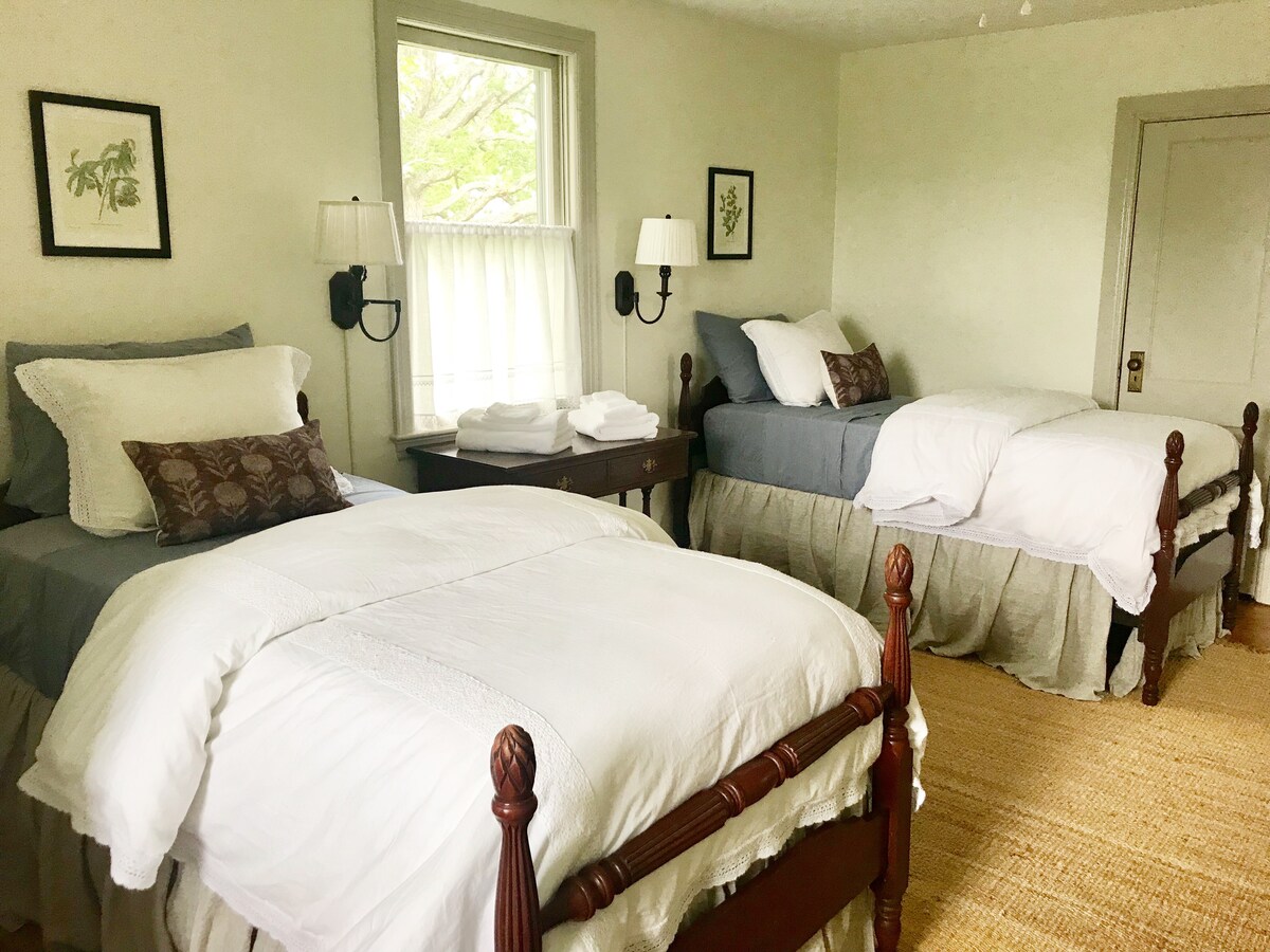 ห้องนอนชั้นบนมีเตียงโบราณไม้มะฮอกกานีคู่รวบรวมกระโปรงผ้าลินินและปลอกผ้านวมสีขาวด้านล่าง