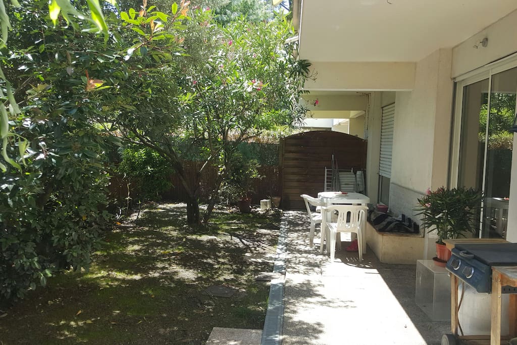 jardin privatif arboré avec table chaises et banc