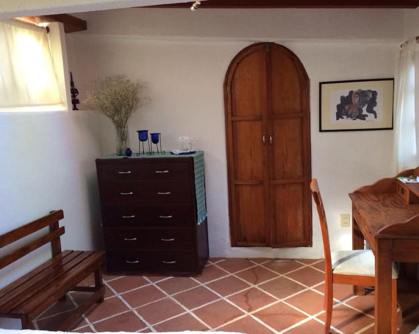 Escritorio, cajonera y puerta que lleva al baño desde la habitación