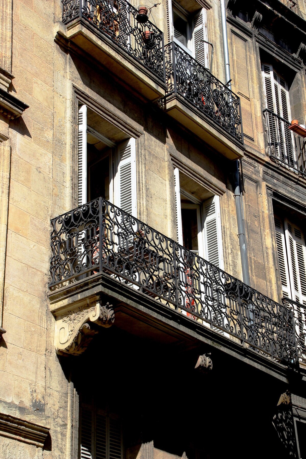 A historic building facade is detailed with intricate wrought-iron balconies. The stone exterior reflects the craftsmanship of the 18th century, with shuttered windows that offer a sense of charm. The architectural features highlight the building's connection to the surrounding historical context.