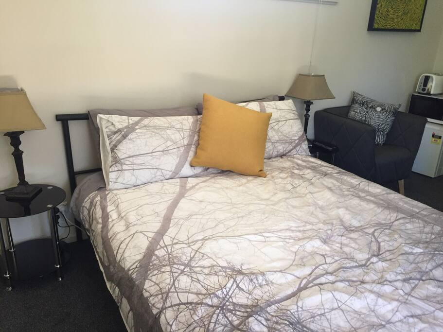 Comfortable bed with view through sliding doors of private seating area