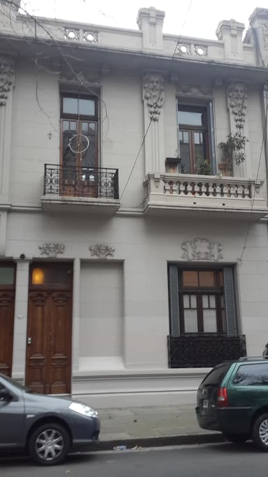 Puerta de entrada, y balcón con plantas del living-biblioteca, espacio compartido