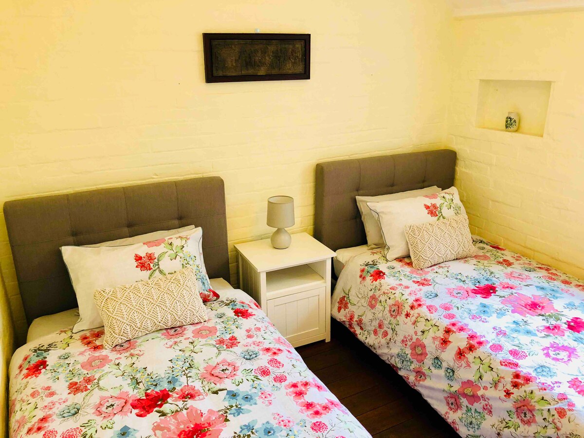 Segundo dormitorio con 2 camas individuales tamaño king, espacio para colgar ropa y espejo de longitud de pared. 