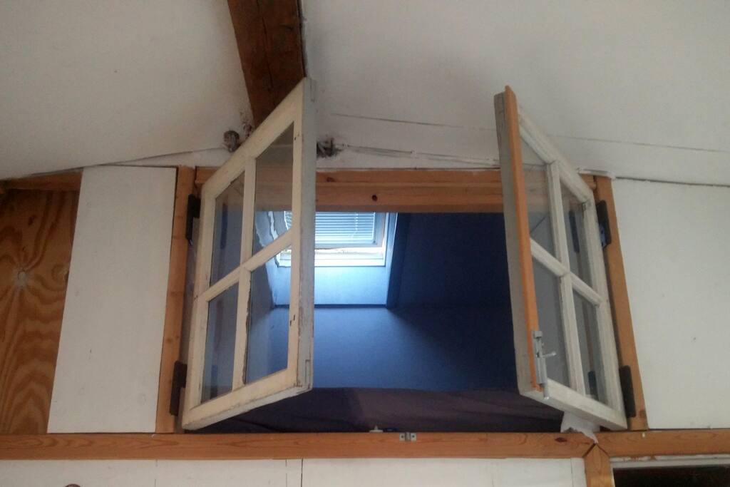 The loft with a double bed, a view of the lounge and a view of the stars