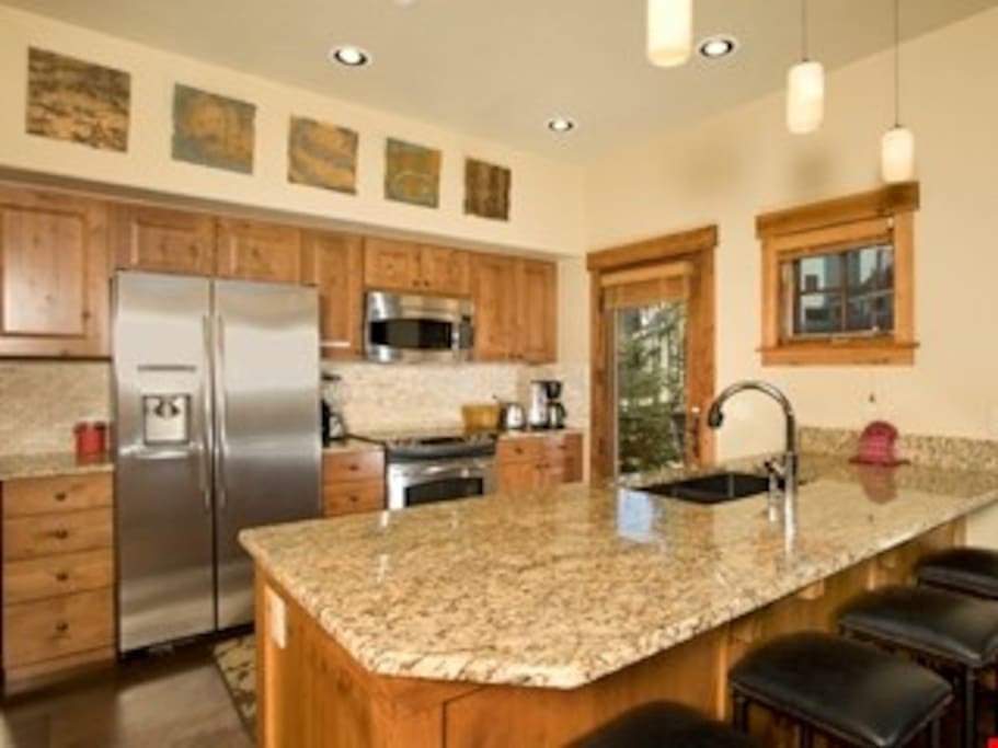 The fully-equipped kitchen features granite countertops, stainless steel appliances and a breakfast bar.