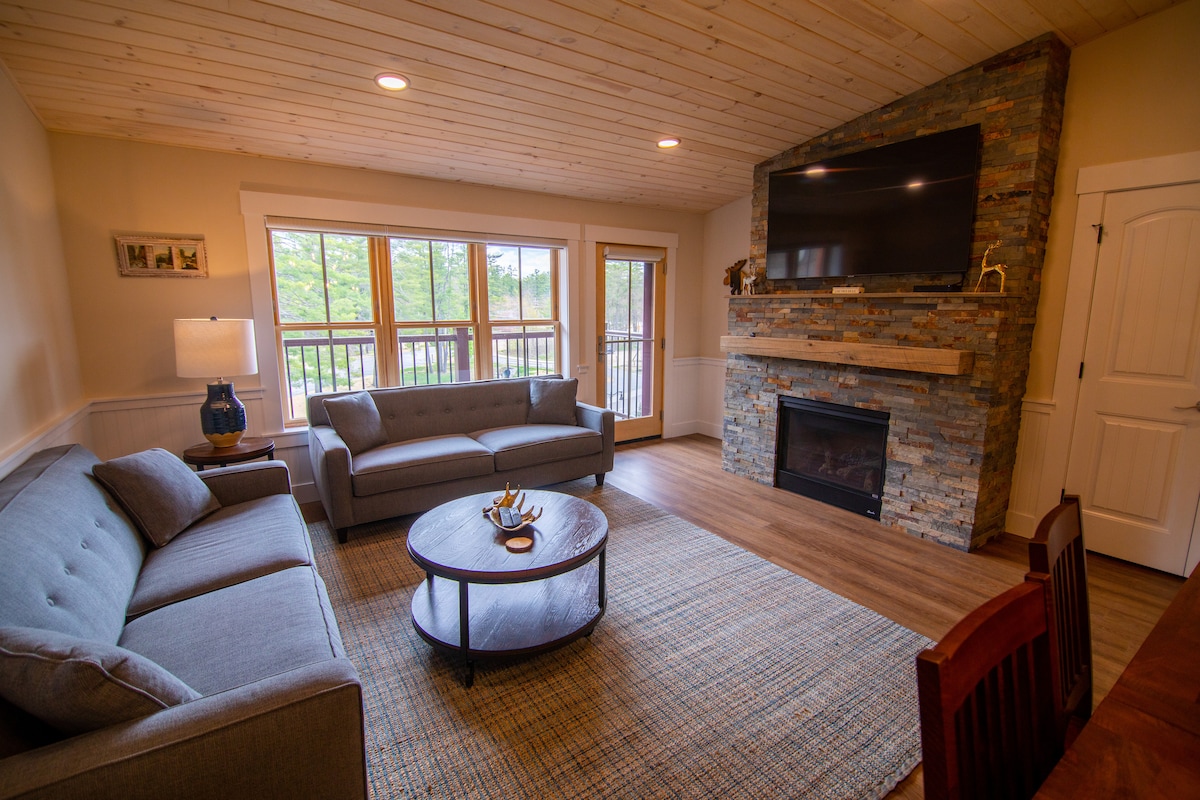 Sala de estar de concepto abierto, comedor y cocina.  Balcón privado con vistas distantes a las montañas. Chimenea de gas