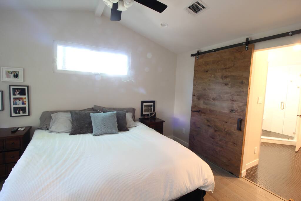 King bed master suite with wide opening through the barn door into the bathroom with a private toilet room and double vanity.