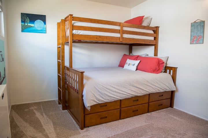 El dormitorio 2 cuenta con dos camas individuales en la parte superior queen en la parte inferior. También incluye aire acondicionado, TV inteligente y consola de juegos, armario/cómoda.