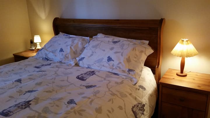 ️ Comfortable primary bedroom with warm wood accents and cozy bedding and ensuite.