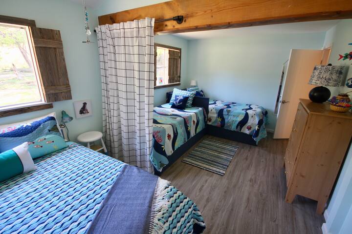 Cama de dos camas y cama de matrimonio. La cortina de privacidad se tira a mitad de camino.
