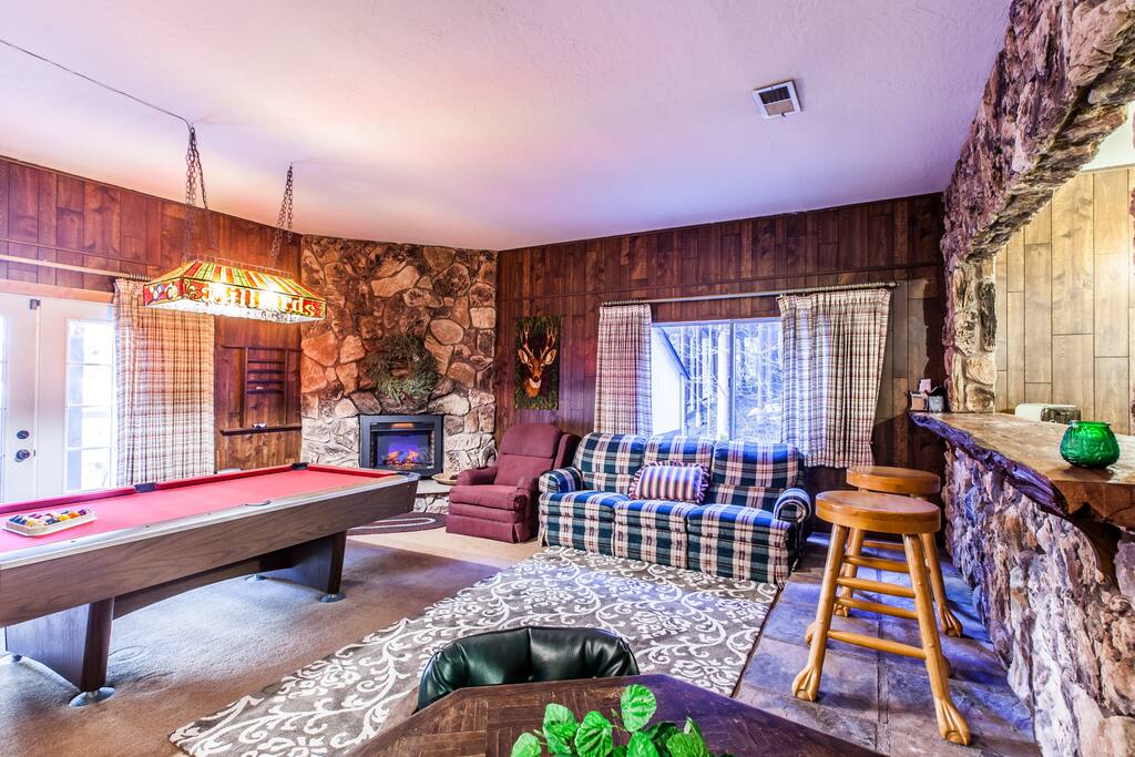 Living room with pool table and fireplace surrounded by rock