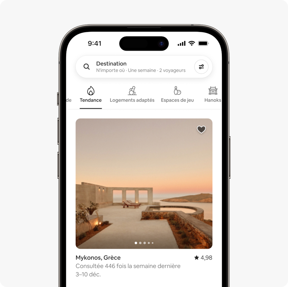 Un ordinateur portable et un téléphone montrent la page d'accueil d'Airbnb avec deux rangées de logements d'une nouvelle catégorie de l'édition hiver Airbnb intitulée Tendance, qui propose des annonces qui ont récemment souvent été consultées.