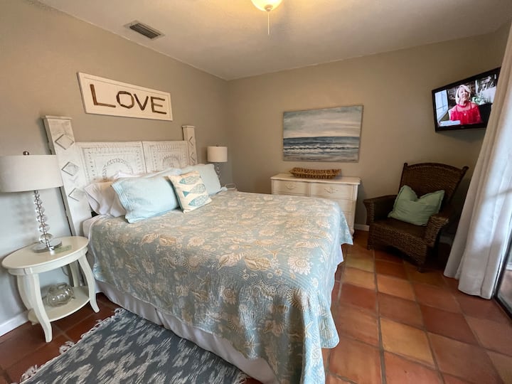 Master bedroom downstairs with a queen size bed and mounted television.  Bedroom opens to patio. 
