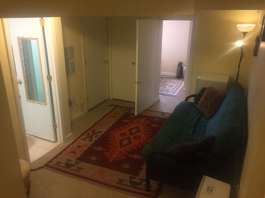 Living space with futon, can be folded out to accommodate 1-2 more people. Mini fridge (has been updated since photo) in corner, laundry through closed door.