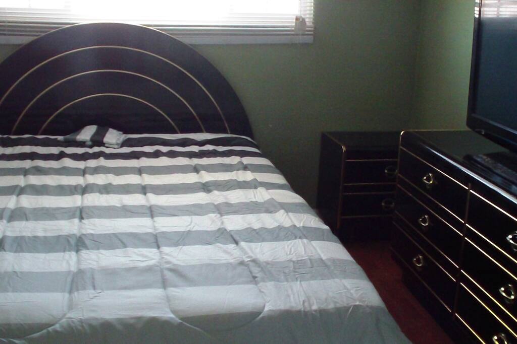 Bright room with Queen bed, Dresser and TV.