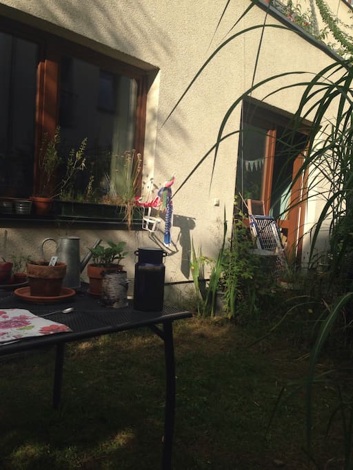 Der Wohnungseingang, daneben ein kleines Grünstück mit Tisch zum Draussensitzen